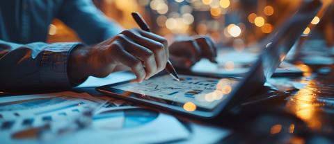 A person at a computer uses a stylus on a curved laptop