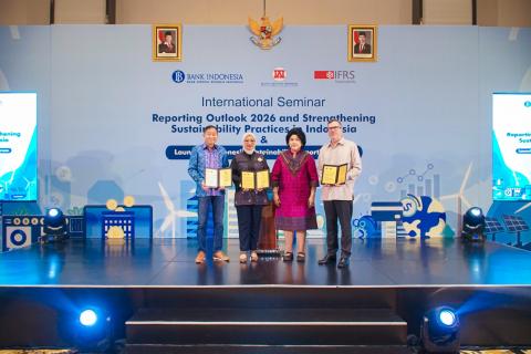 A group of four standing onstage, holding documents
