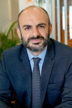A man with a beard in a suit, smiling at the camera
