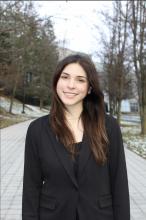 A woman in a black blazer standing smiling at the camera