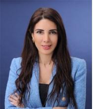 A woman wearing a light blue blazer smiling at the camera