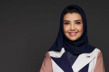 A woman wearing a black headscarf and a tan jacket