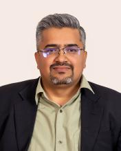 A man with a goatee and glasses looking at the camera