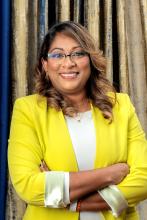 A woman wearing a yellow blazer smiling at the camera
