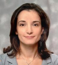 A woman with shoulder length hair smiles at the camera
